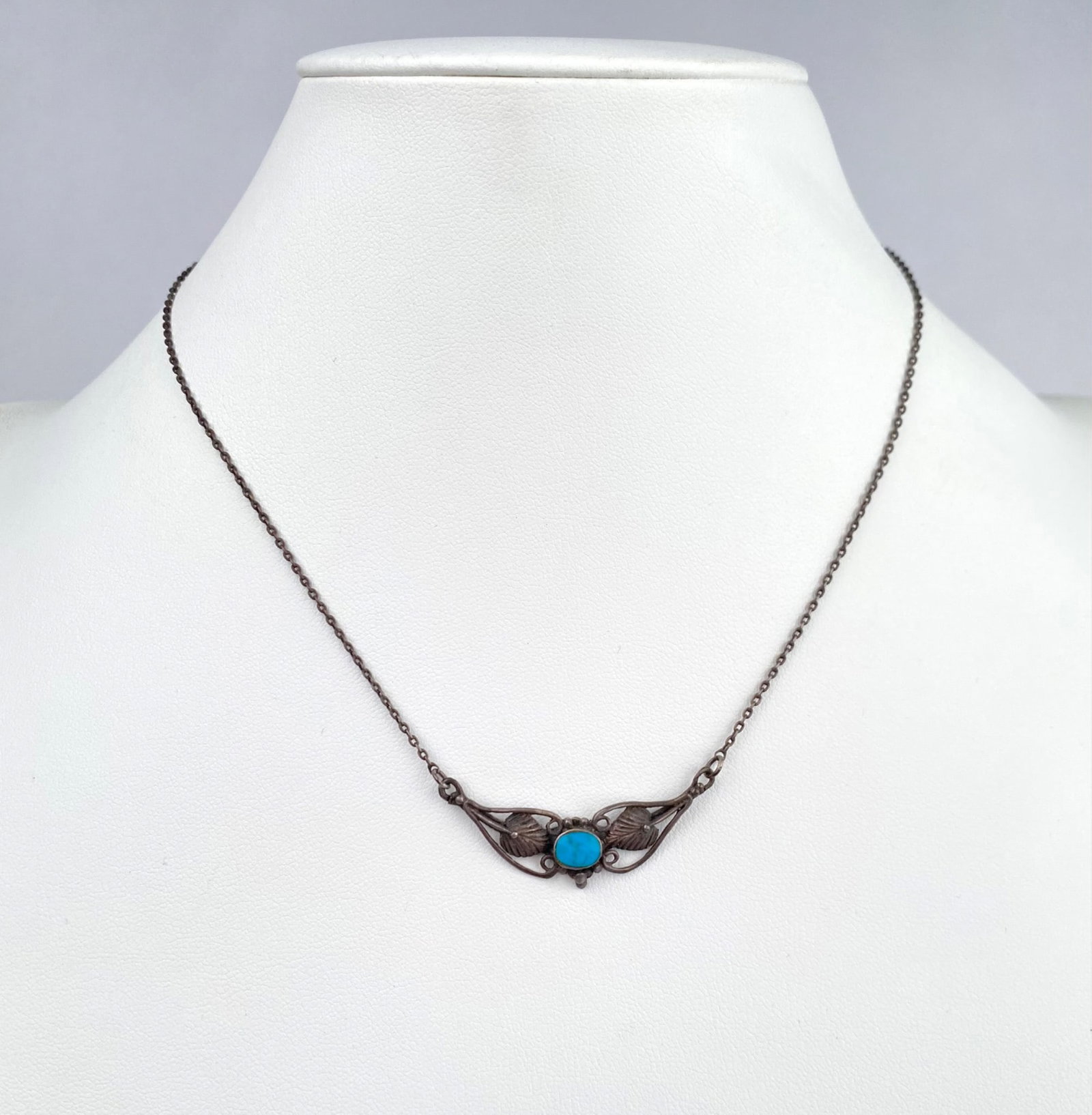 Silver Necklace With Filigree Design and Turquoise Accent: Silver necklace featuring an elegant filigree design and a central turquoise cabochon stone. The piece showcases intricate craftsmanship in the metalwork, with a lightweight chain and a spring clasp c
