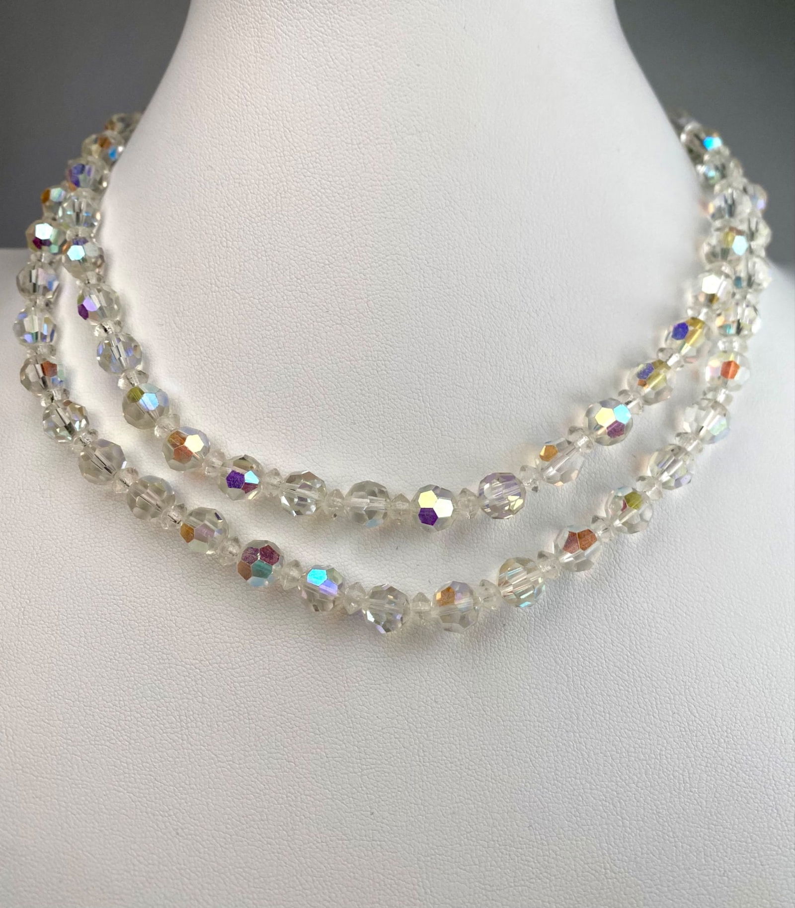 Vintage Double Strand Aurora Borealis Crystal Bead Necklace: Vintage double strand aurora borealis crystal necklace. Featuring faceted clear glass beads with a luminous iridescent finish, the necklace reflects hues of purple, gold and blue under the light. The