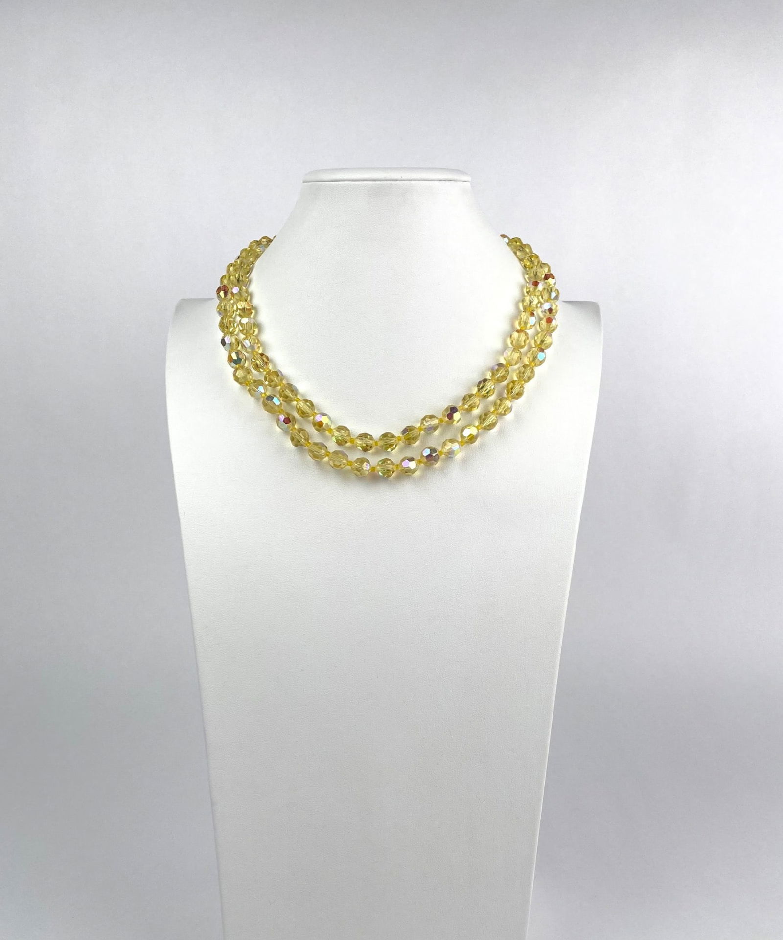 Double Strand Yellow Faceted Bead Necklace with Rhinestone Clasp: Double strand necklace featuring yellow faceted beads with an iridescent finish, secured by an ornate rhinestone clasp. The necklace displays a vibrant and reflective appearance, enhancing its eleganc