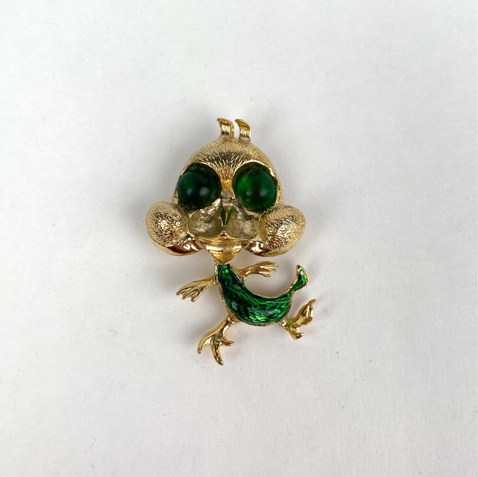 Vintage Gold Tone Brooch with Enamel Detailing Marked Austria: Gold tone brooch featuring a whimsical design with green enamel detailing and large bubbly green gemstone style eyes. Marked Austria on the reverse, the brooch has a secure pin closure. In good condit
