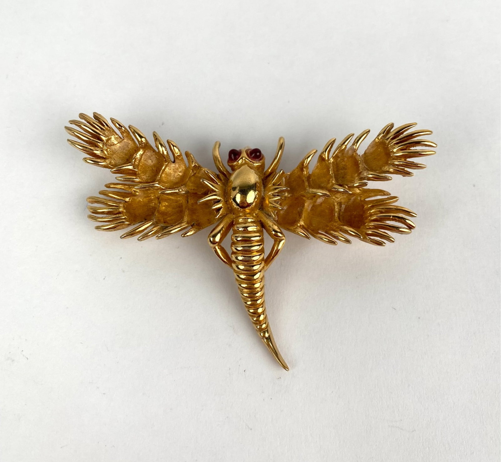 Boucher Gold Tone Articulated Dragonfly Brooch: Gold-tone brooch by Boucher in an articulated dragonfly design, featuring detailed textured wings and body. The piece is set with red rhinestone eyes and marked Boucher with model number on the revers