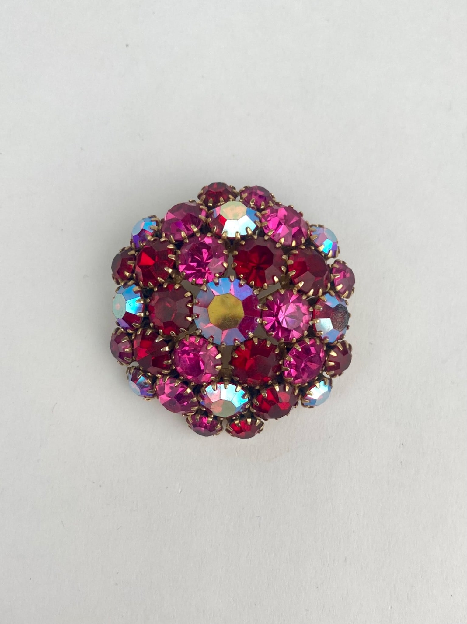 Vintage Domed Brooch with Red and Aurora Borealis Rhinestones: Gold tone domed brooch featuring multiple prong set red and aurora borealis (AB) rhinestones in a clustered arrangement. Pinback is securely attached with a functional clasp. In good condition. Please