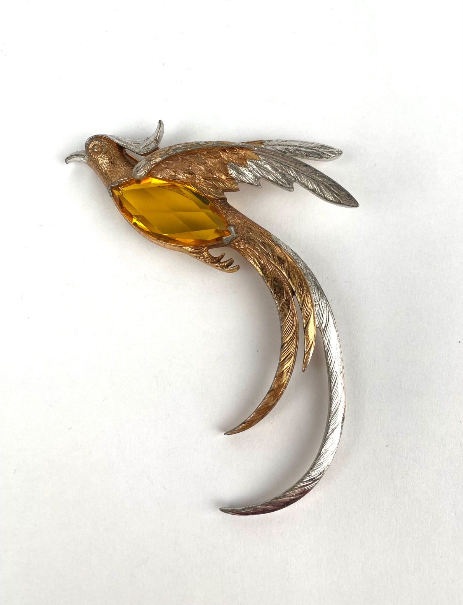 Two Tone Bird Brooch with Yellow Faceted Stone: Gold-tone and silver-tone brooch designed in the shape of a bird with accentuated long wings and tail feathers. The piece features a large yellow faceted center stone, likely glass, held in a prong se