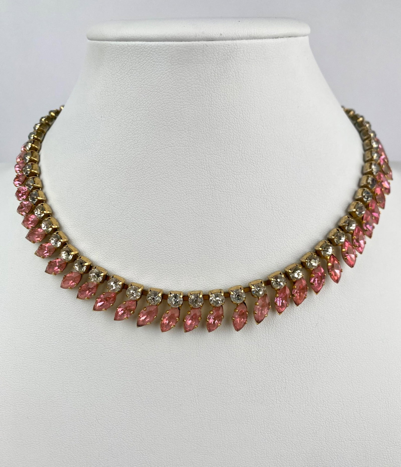 Vintage Pink and Clear Rhinestone Choker Necklace: Classic vintage rhinestone choker necklace featuring alternating rows of clear round stones and vivid pink navette cut rhinestones in a fringe like design. Set in a gold tone setting, the necklace clo