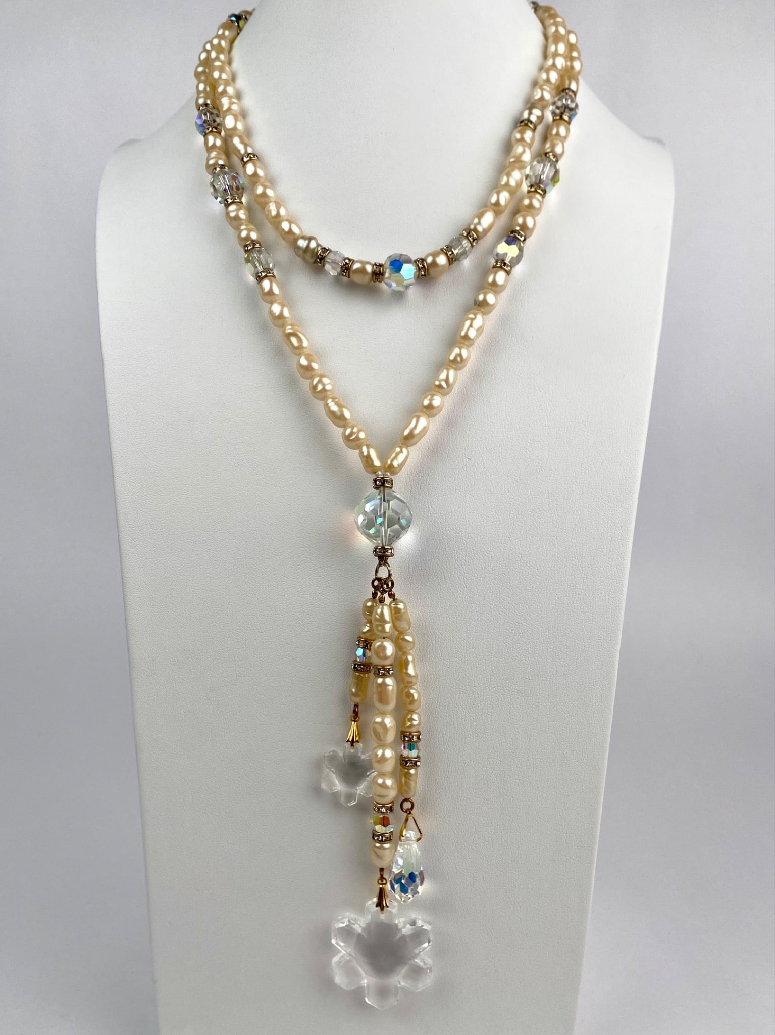 Vintage Faux Pearl and Crystal Dangle Necklace: Vintage necklace features a design of creamy faux pearls accented with faceted aurora borealis crystal and gold tone rhinestone rondelles. At the center hangs a dramatic drop composed of a large facet