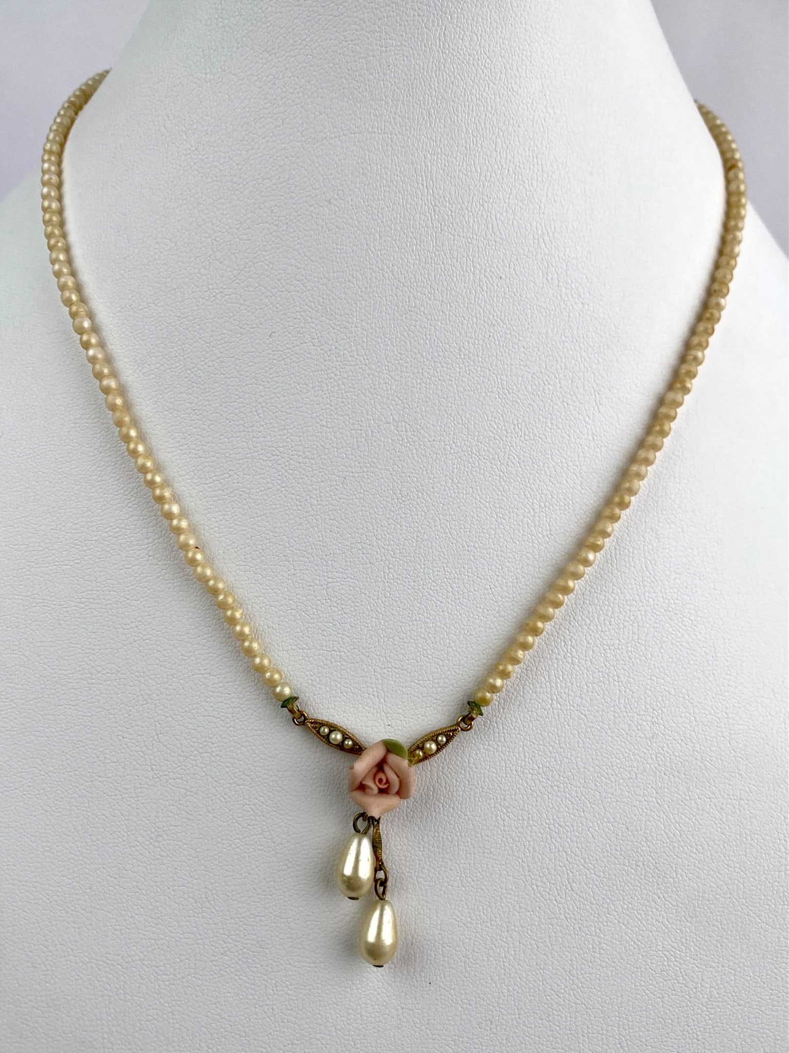 1928 Jewelry Co Faux Pearl Necklace with Rose Drop: Vintage necklace by 1928 Jewelry Co featuring a strand of faux pearls with a delicate centerpiece composed of a pale pink resin rose, flanked by seed pearl accented findings and two teardrop faux pear