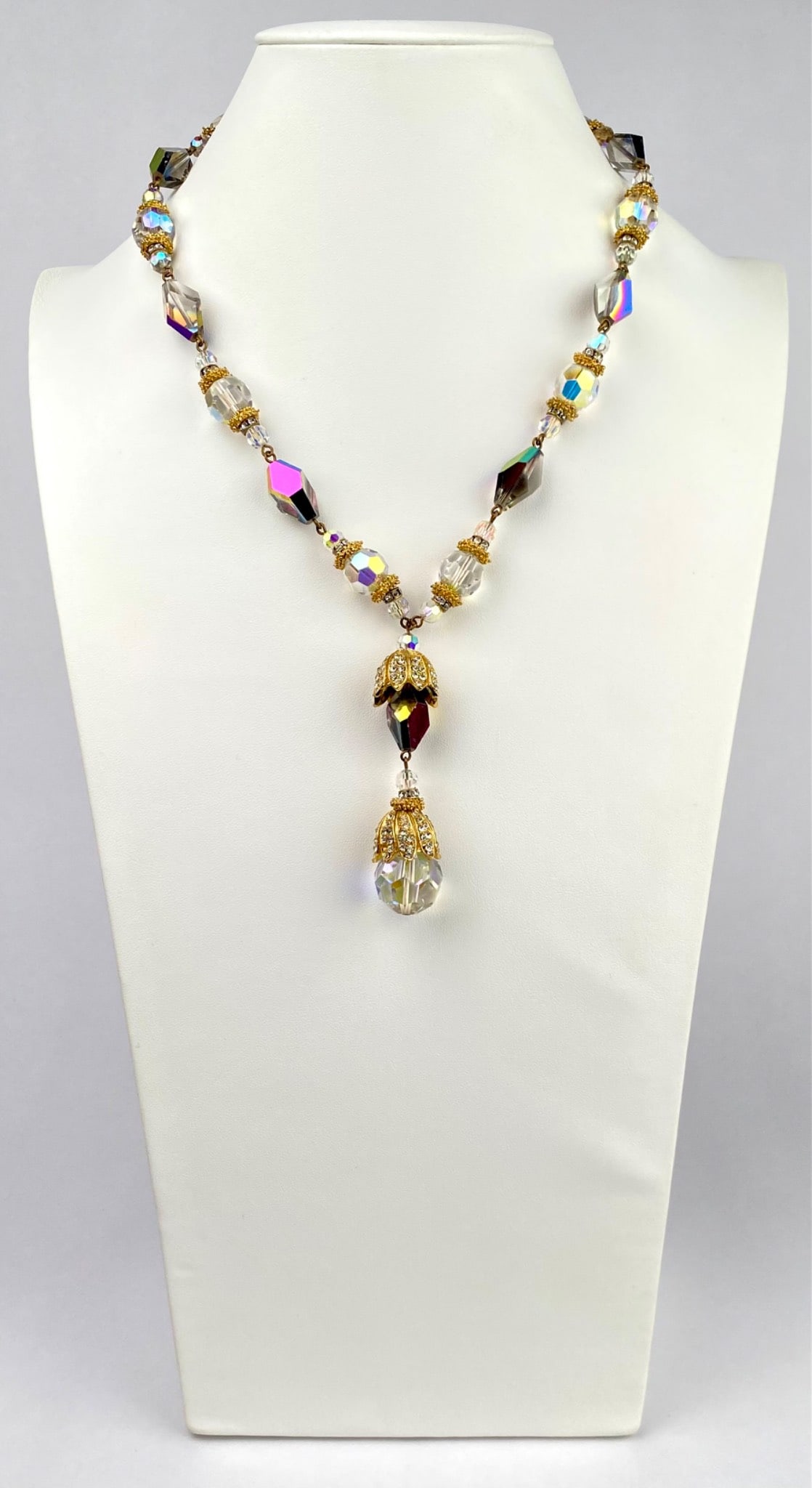 Vintage Hattie Carnegie Aurora Borealis Crystal Drop Necklace: This is a vintage Hattie Carnegie necklace featuring faceted aurora borealis and clear crystal beads accented with ornate gold tone filigree caps. The design culminates in a dramatic Y drop pendant wi