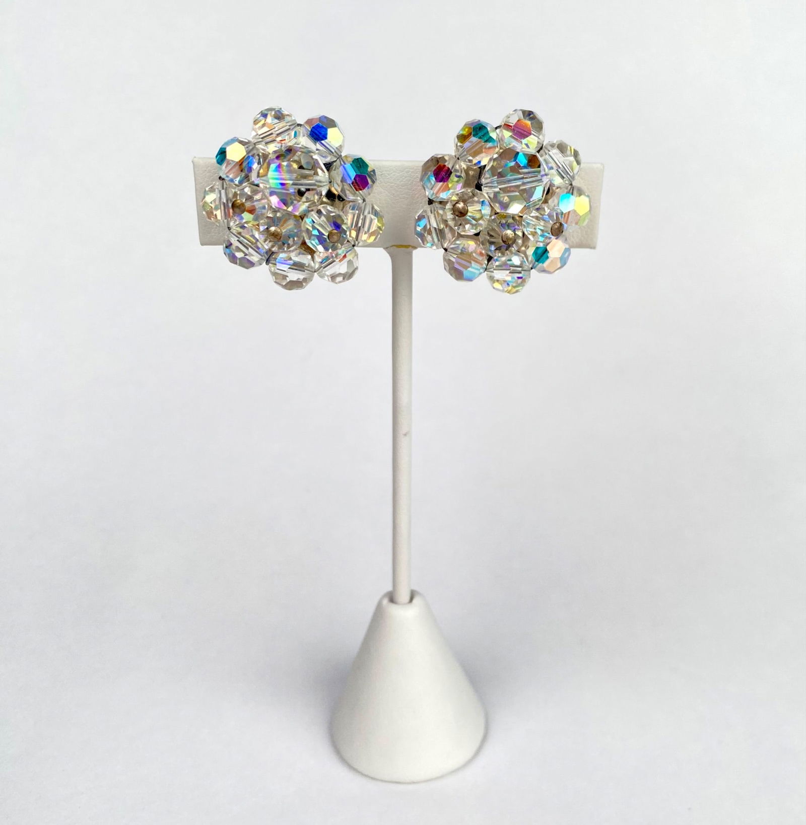 Vintage Pair of Aurora Borealis Crystal Cluster Clip On Earrings: Aurora Borealis crystal clip on earrings featuring clusters of faceted, iridescent beads. The backing and clips are fitted with a silver tone metal finish and soft padding for comfort. Earrings are in