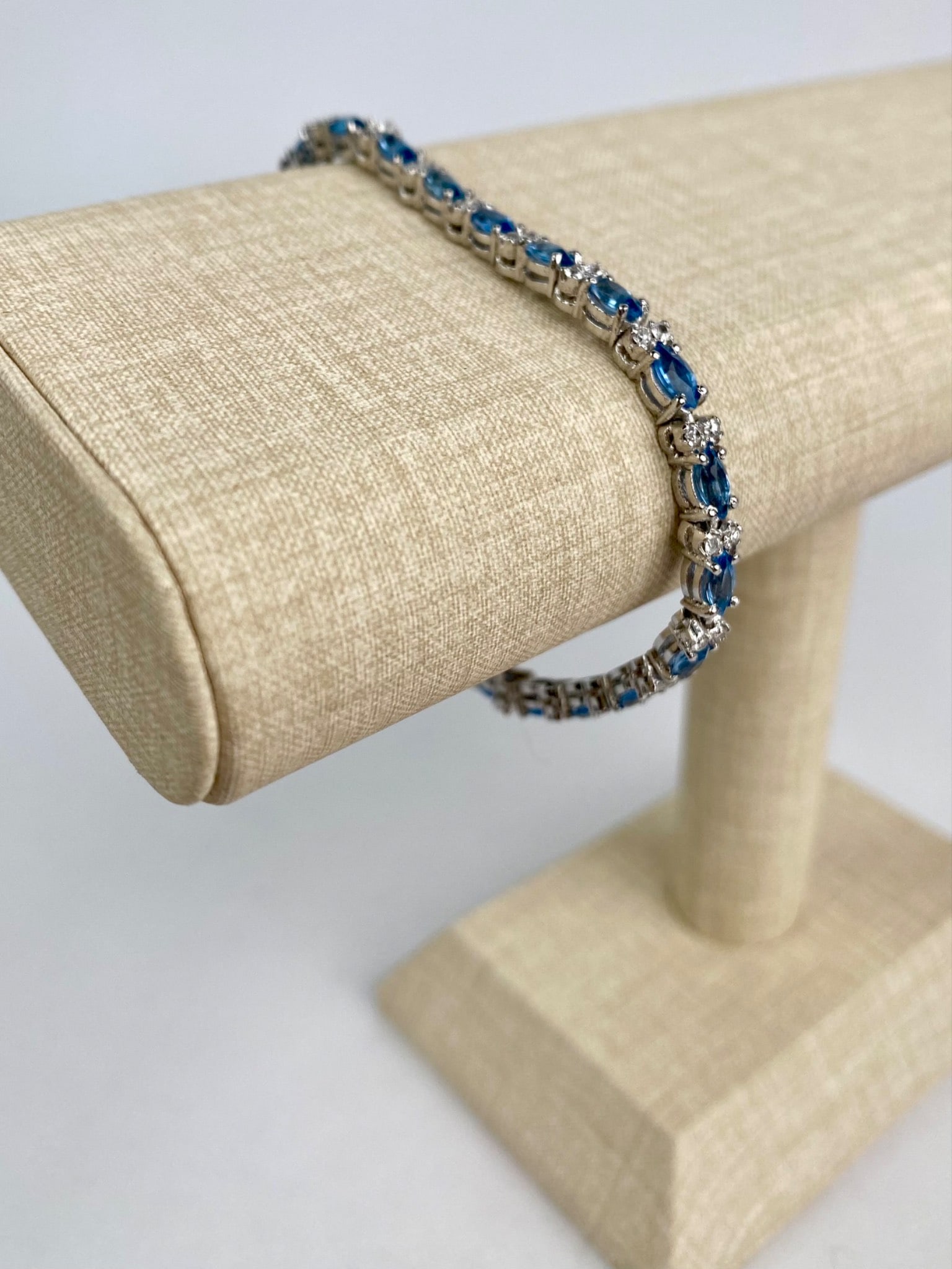 Sterling Silver Blue Topaz and CZ Tennis Bracelet: Sterling silver tennis bracelet featuring alternating marquise cut blue topaz stones and clusters of round clear cubic zirconia. The stones are set in a sleek channel style setting. The piece is hallm