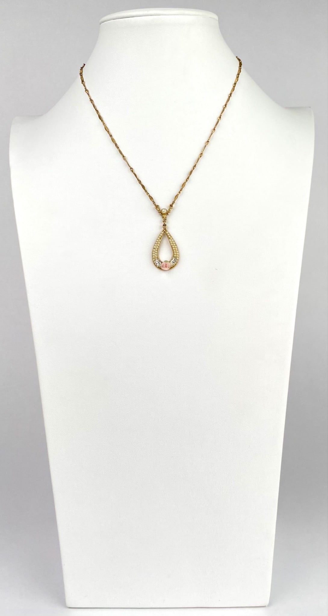 Vintage 1928 Jewelry Co Teardrop Pendant Necklace with Faux Pearls: Gold tone necklace featuring a teardrop shaped pendant adorned with pearl accents, crystal embellishments, and a central pink rose detail by 1928 Jewelry Co. Back clasp and tag marked 1928. Necklace i