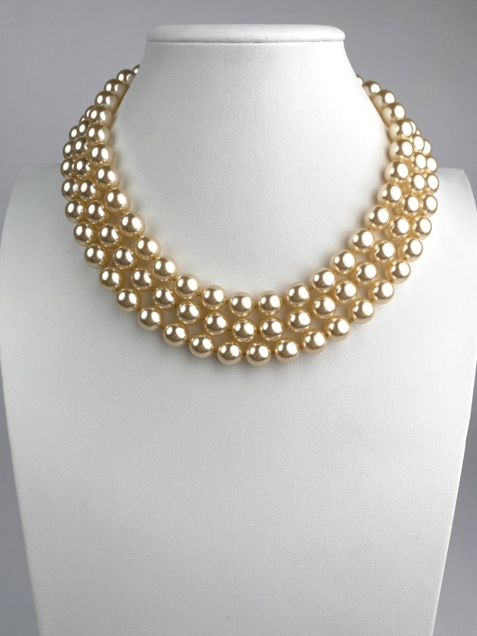 Vintage Kenneth Jay Lane Three Strand Faux Pearl Collar Necklace: Vintage three strand collar necklace featuring cream tone faux pearls. The necklace is secured with a gold tone toggle clasped marked KJL for Kenneth Jay Lane, known for his iconic costume jewelry des