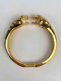 Kenneth Jay Lane gold tone spring cuff bangle featuring two panther heads with open mouths,