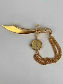 Kenneth Jay Lane sword brooch featuring a gold tone scimitar encrusted with clear rhinestones along