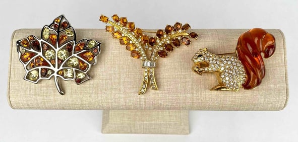 Lot of three brooches by Nolan Miller. One brooch is a squirrel brooch with gold tone metal,