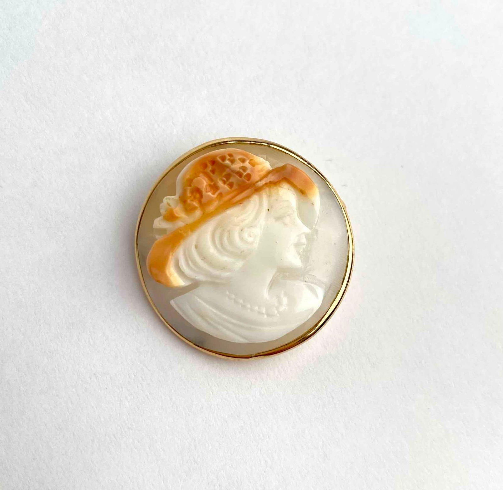 Italian cameo pendant brooch, featuring the profile of a lady in a broad brimmed floral hat, carved: Italian cameo pendant brooch, featuring the profile of a lady in a broad brimmed floral hat, carved in shell and set in a 14K yellow gold bezel frame. The piece includes a hidden bail for wear as a pe