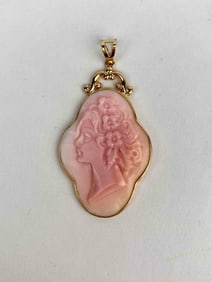 Carved pink shell cameo pendant set in 14K yellow gold. The cameo features a classical female