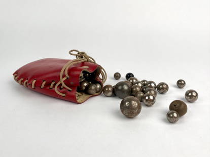 Vintage Metal Marbles in Red Leather Pouch: Set of vintage metal marbles housed in a red leather drawstring pouch. The collection includes marbles in various sizes, crafted from metal with a worn, aged patina, ranging in finish from smooth and