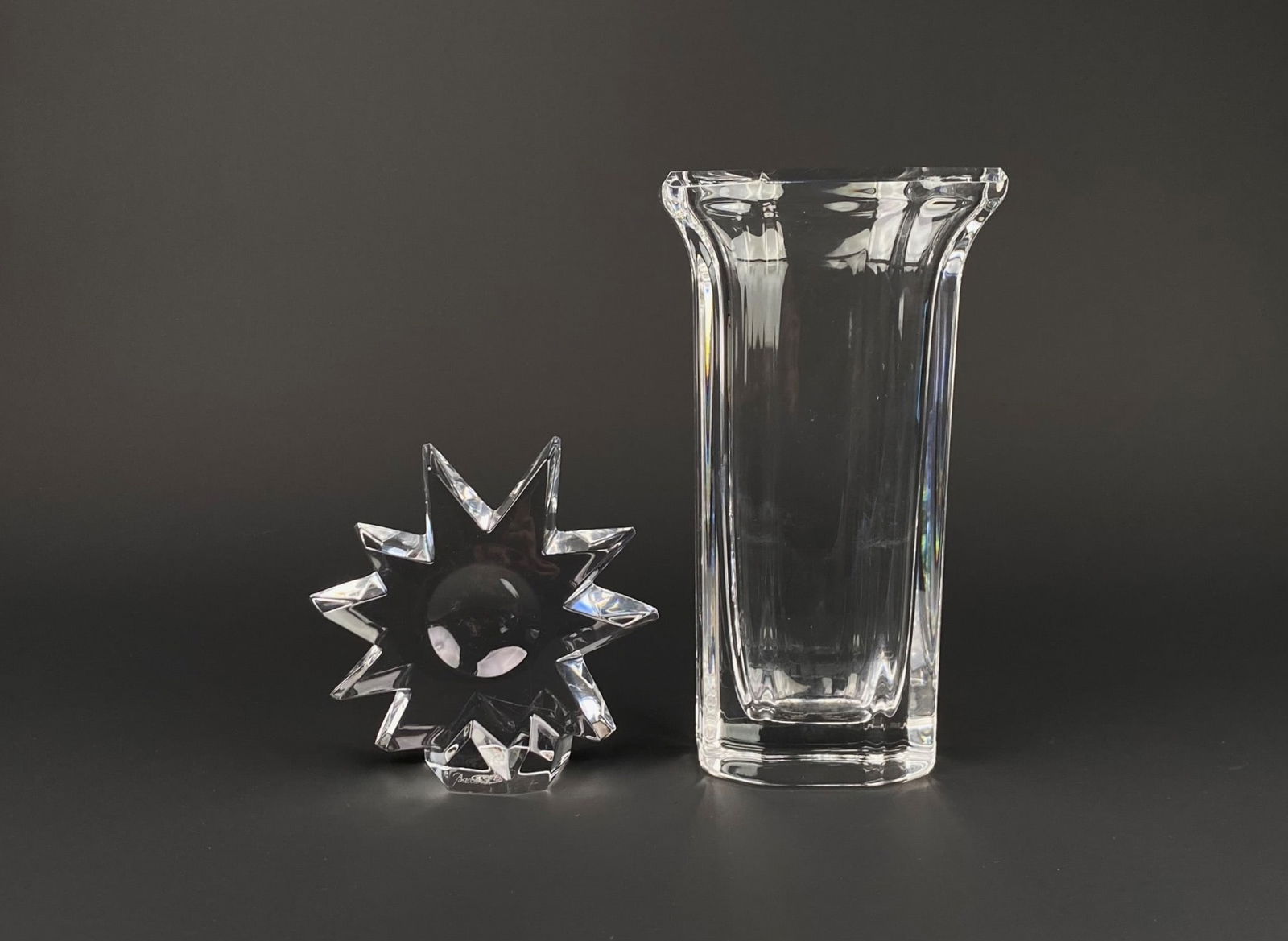 Kosta Boda Vase and Baccarat Starburst Figure: Set includes a Kosta Boda vase and a Baccarat starburst figure. The Kosta Boda vase bears markings on the base and features a flared hexagonal rim with a modern, clear glass design. The Baccarat cryst