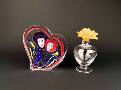 Daum Perfume Bottle and Spirit of Love Heart Glass Sculpture: Daum perfume bottle with clear glass body, featuring a flower shaped stopper in amber colored glass. Accompanied by the Spirit of Love heart shaped sculpture showcasing two hand painted faces with vib
