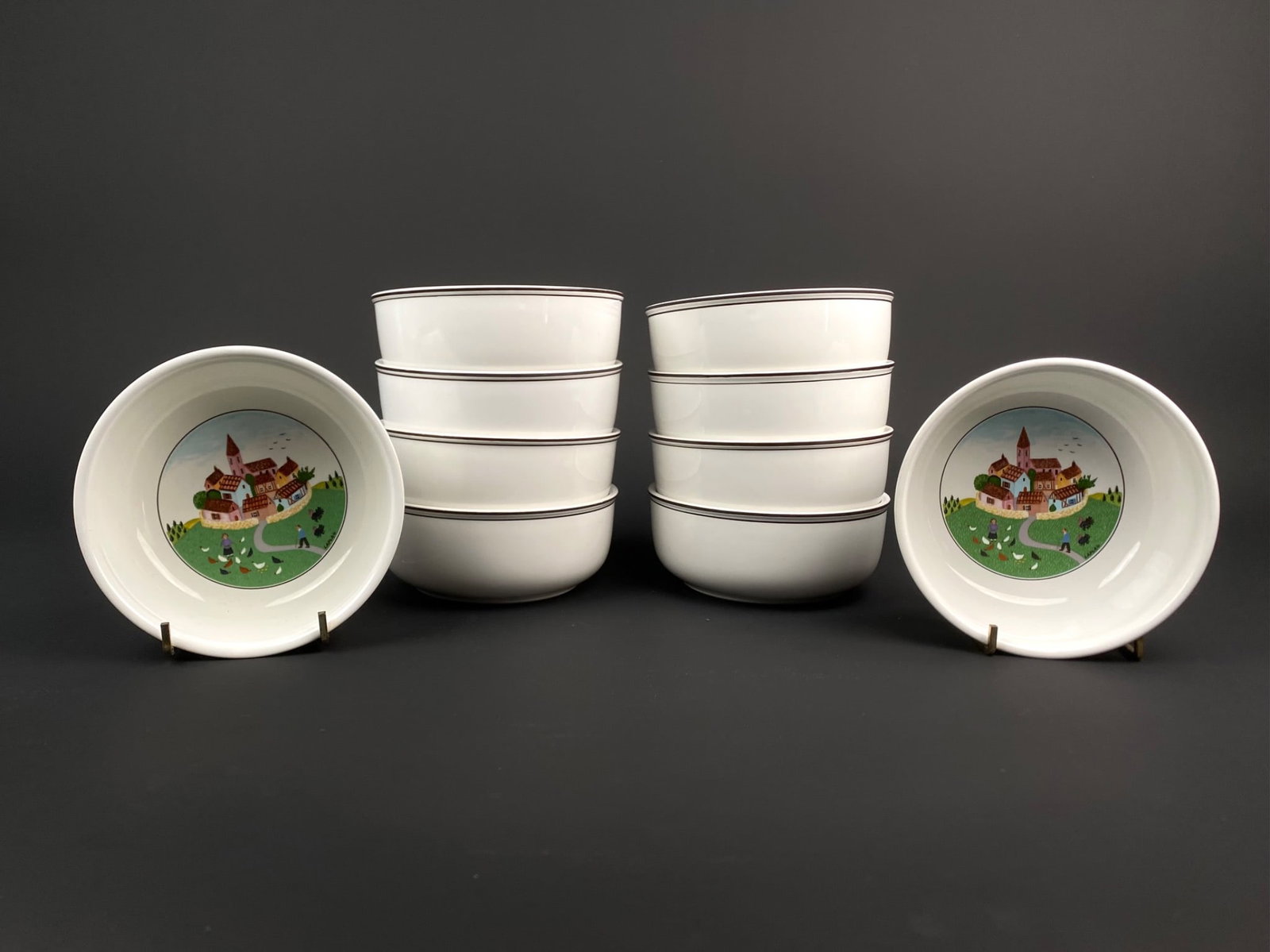Set of 10 Villeroy & Boch 'Design Naif' Bowls: Set of ten fine porcelain bowls from the Design Naif collection by Villeroy and Boch featuring artwork by Gerard Laplau. Each bowl showcases a pastoral village scene. These bowls are marked Villeroy a