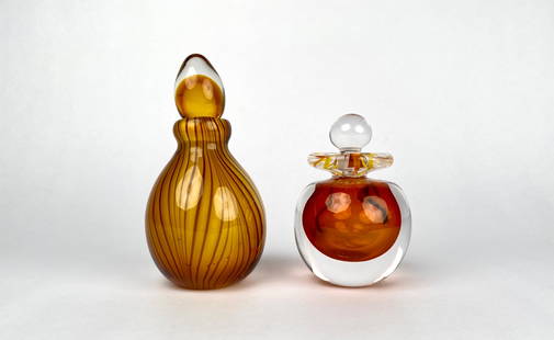 Pair of Perfume Bottles Including Murano Art Glass: A lot of two amber colored art glass perfume bottles with stoppers. One features a clear stopper with an internal orange and yellow swirl design and etched signature and 1995 on the base. The second,