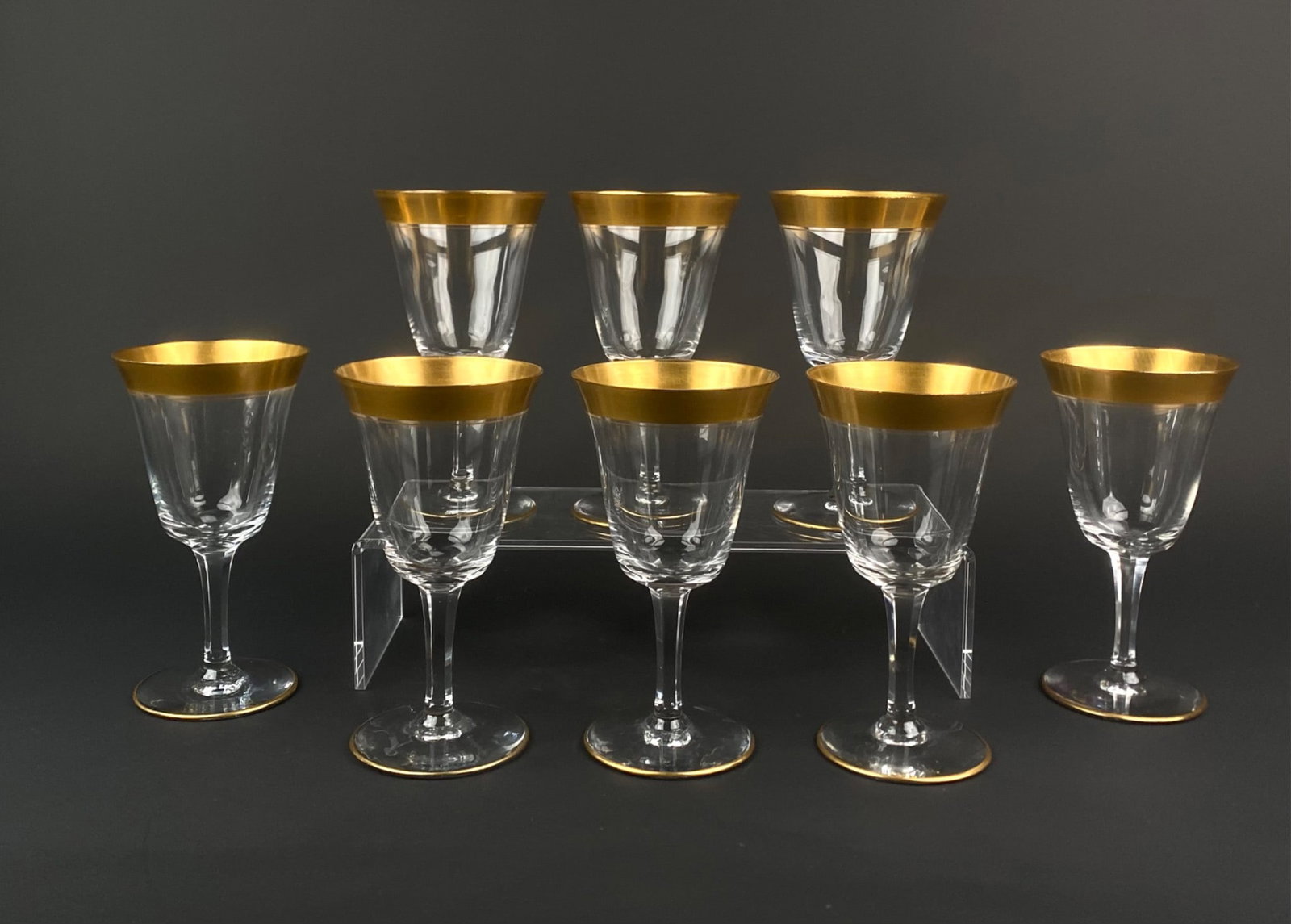 Set of Eight Vintage Gold Banded Crystal Wine Glasses: Set of eight vintage crystal wine glasses featuring faceted bowls and gold banded rims and feet. The clear crystal bodies are paneled with a wide satin finished gold band adorned on the rim. Each glas