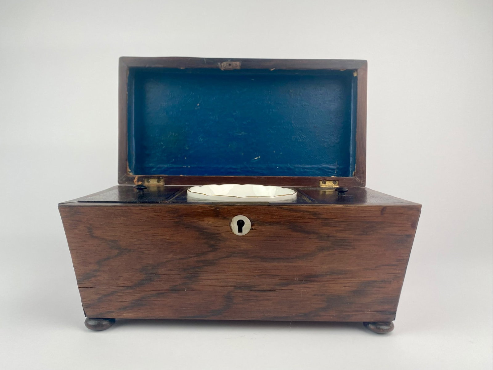 Georgian Mahogany Sarcophagus Tea Caddy with Porcelain Bowl (1780): Georgian period tea caddy, circa 1780, crafted in mahogany with a sarcophagus form body raised on four flattened bun feet. The top features a beveled lid with a carved rectangular handle and opens to 