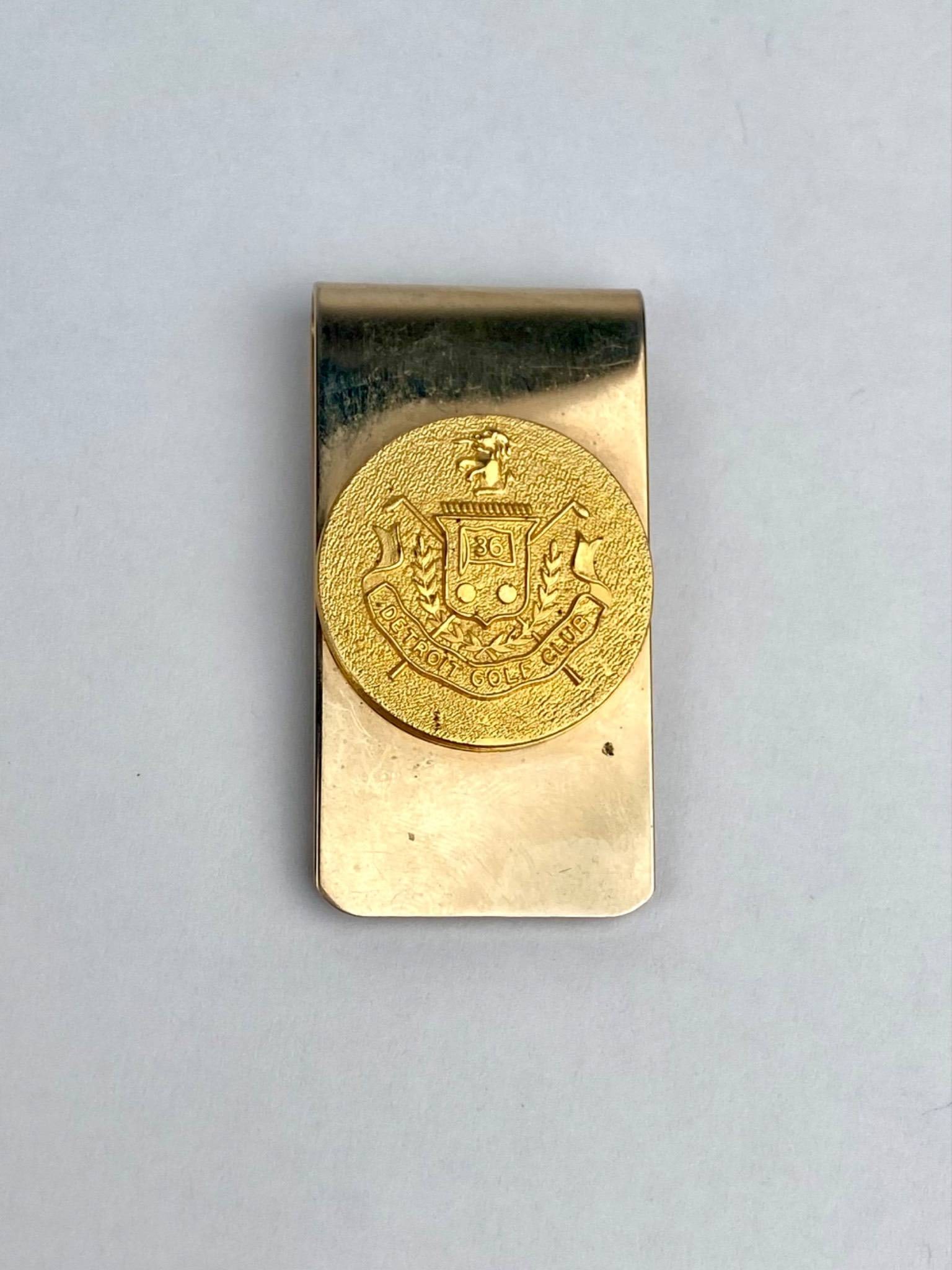 Vintage Detroit Golf Club Gold Tone Money Clip: Vintage gold tone money clip featuring a raised medallion embossed with the seal of the Detroit Golf Club, complete with crossed golf clubs, laurels, and a prominent 36 insignia. The clip has surface 