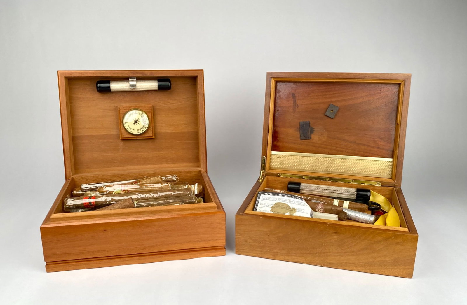 Two Wooden Humidors with Assorted Cigars and Accessories: Wooden humidors, one made by Heritage (USA) and the other by Decatur Industries, Inc. Both boxes include hygrometers and various cigar accessories. One humidor contains a collection of assorted wrappe