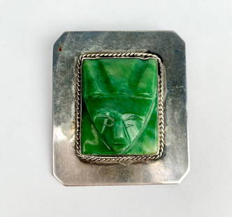 Mexican Sterling Silver Brooch with Green Face Carving: Mexican sterling silver brooch featuring a carved green stone face centerpiece accented with a rope style silver border. The piece is stamped SILVER MEXICO on the back. Includes a secure pin and