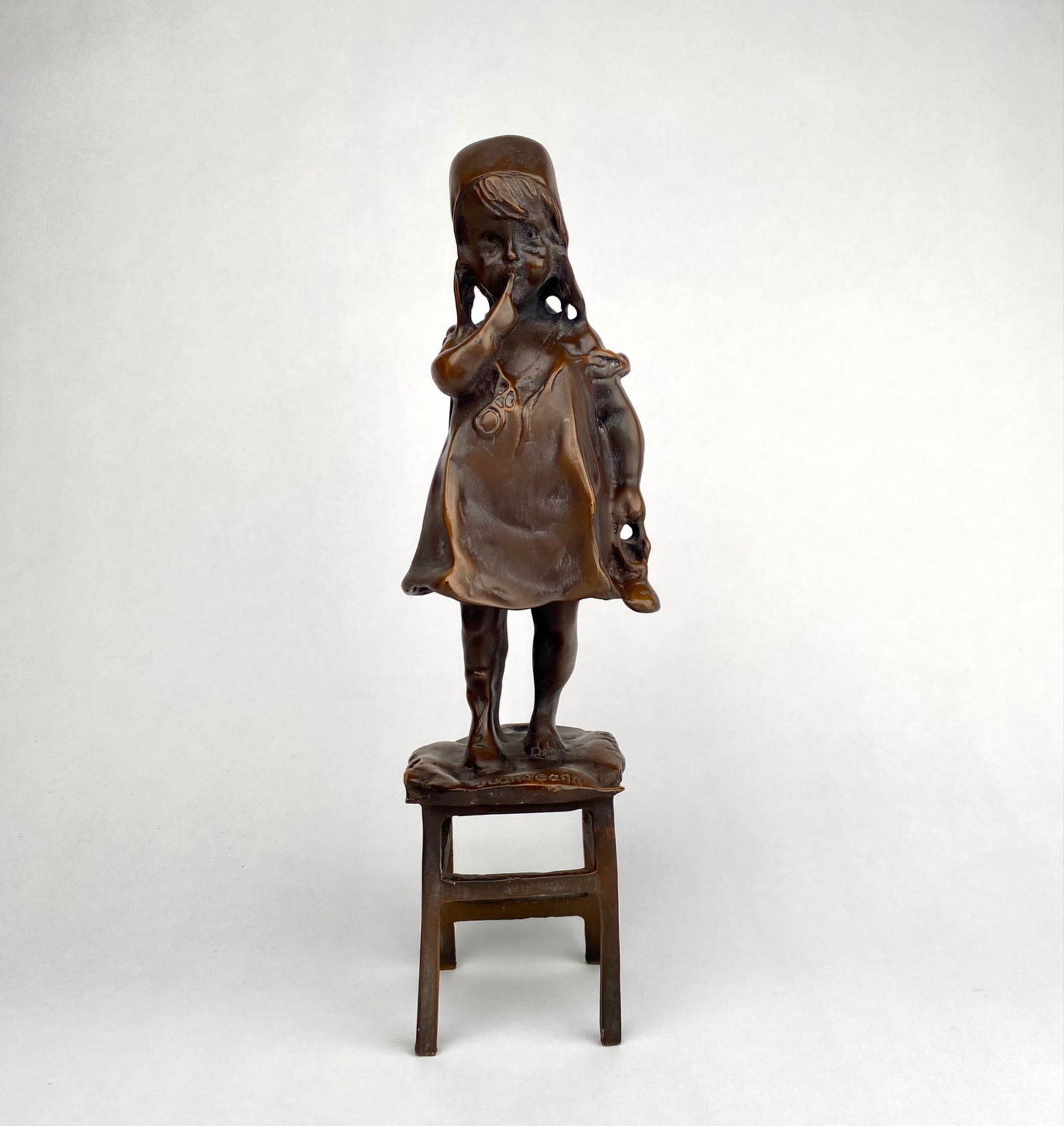 Juan Clara Ayats Bronze Sculpture of a Young Girl on a Stool: Bronze sculpture depicting a young girl standing on a stool, signed Juan Clara on the base. The figure showcases fine detailing and craftsmanship, with the girls pose suggesting a playful, childlike d