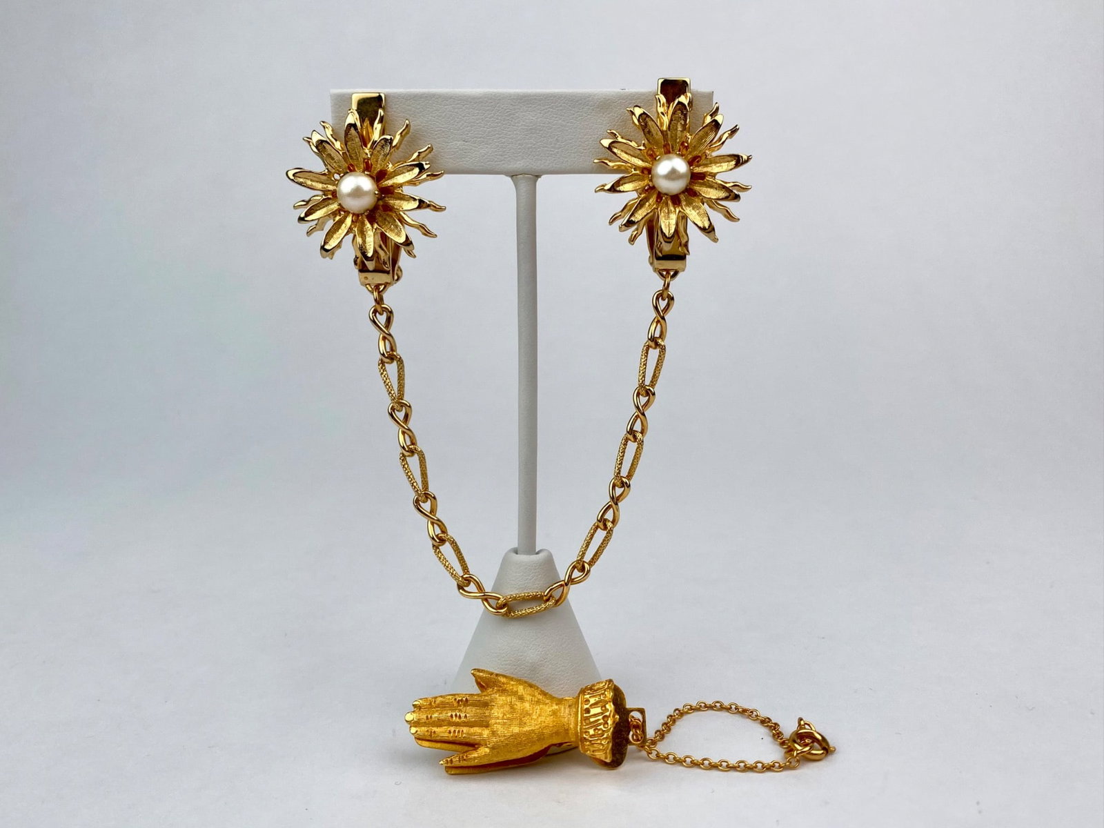 Vintage Gold-Tone Floral Sweater Guard with Hand Clip: Vintage gold-tone sweater guard featuring two floral dress clips joined by a textured chain, each clip is centered with a domed faux pear. The reverse of each clip is marked with U.S. Patent Number 28