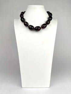 Vintage Cherry Amber Bakelite Bead Necklace: Vintage cherry amber Bakelite bead necklace featuring large, polished, graduated oval beads in a deep translucent red tone. Beads are strung on a red cord and finished with a brass tone screw barrel c
