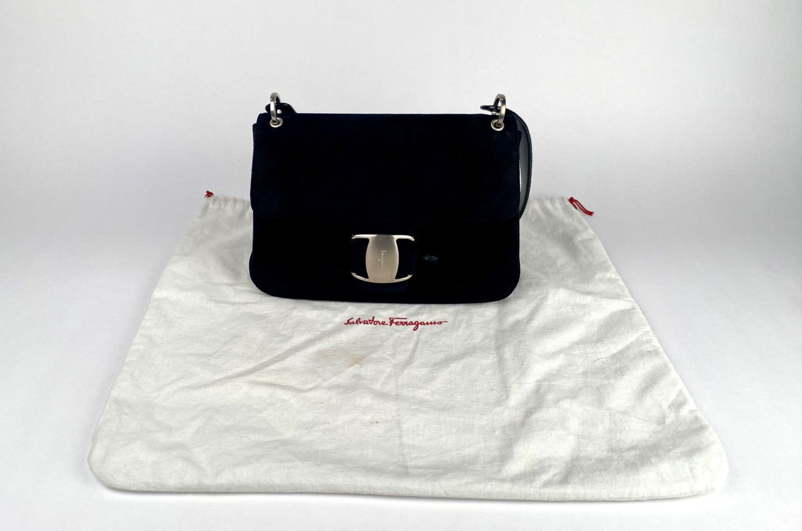 Salvatore Ferragamo Black Suede Handbag with Dust Bag: Salvatore Ferragamo black suede handbag featuring a structured design with a polished silver tone closure engraved with the Ferragamo logo. Includes an adjustable leather shoulder strap and a lined in