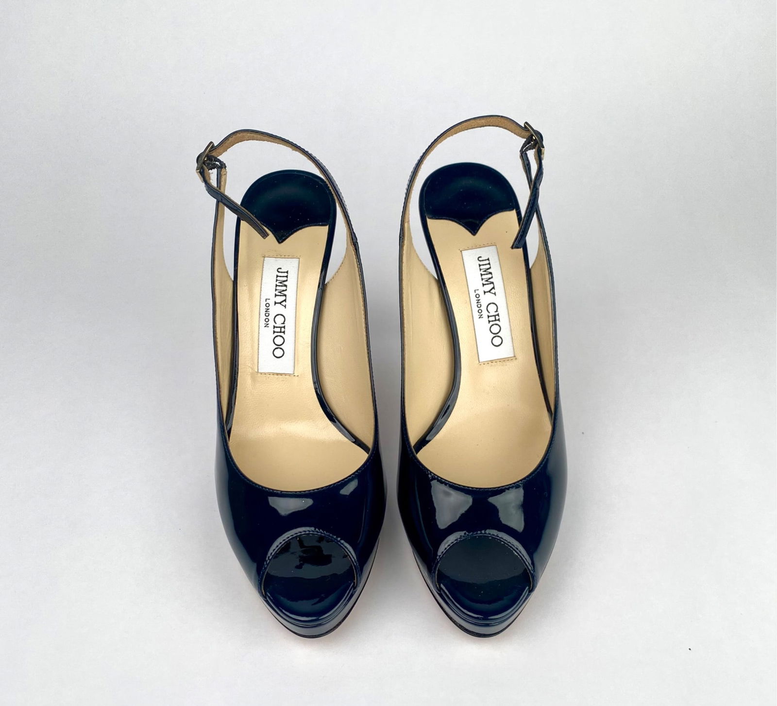 Jimmy Choo Navy Patent Leather Slingback Heels (Size 37.5): Jimmy Choo heels crafted in navy patent leather with a peep toe design and slingback strap. Made in Italy, these shoes feature a beige leather lining, high heels, and a lightly cushioned insole for co
