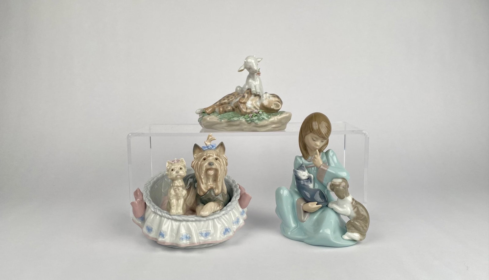 Set of Three Lladr Porcelain Figurines: Three LladrÃ³ porcelain figurines, including: | 1. Lamb and Leopard (model 6926), depicting a lamb resting on a spotted leopard with floral detailing on the base. | 2. Girl with Dog and Cat (model 5