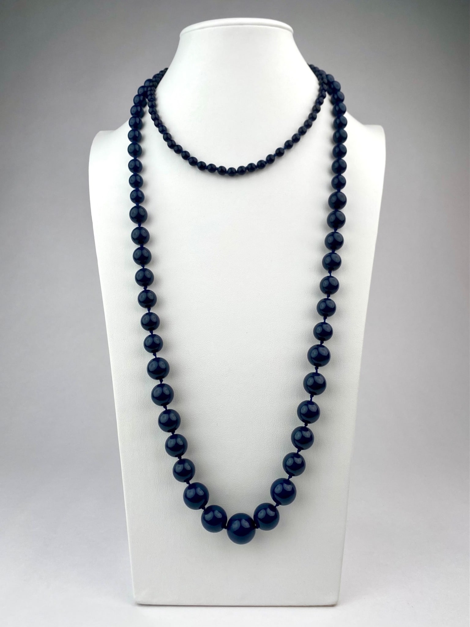 Set of Two Vintage Navy Blue Beaded Necklaces: Pair of vintage navy blue beaded necklaces, one graduated beaded and one uniform beaded. First is a long strand of glossy deep navy blue, graduating in size towards the center. The beads are individua
