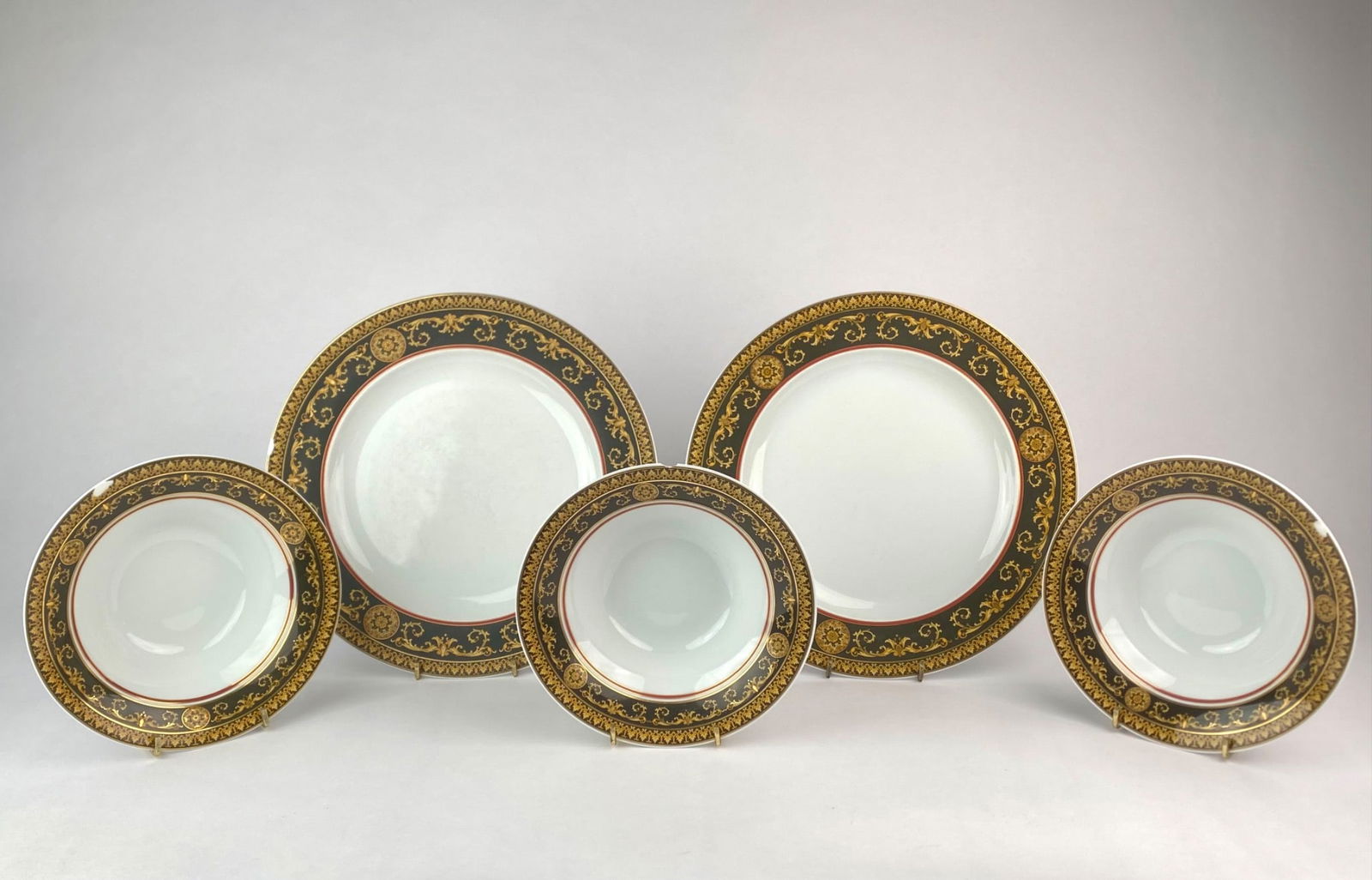 Five-Piece Versace Medusa Porcelain Set with Baroque Border: Five-piece Versace porcelain set from the Rosenthal collaboration, featuring the iconic "Medusa" head logo on the reverse and an Baroque-style border in black, gold and red. The set includes