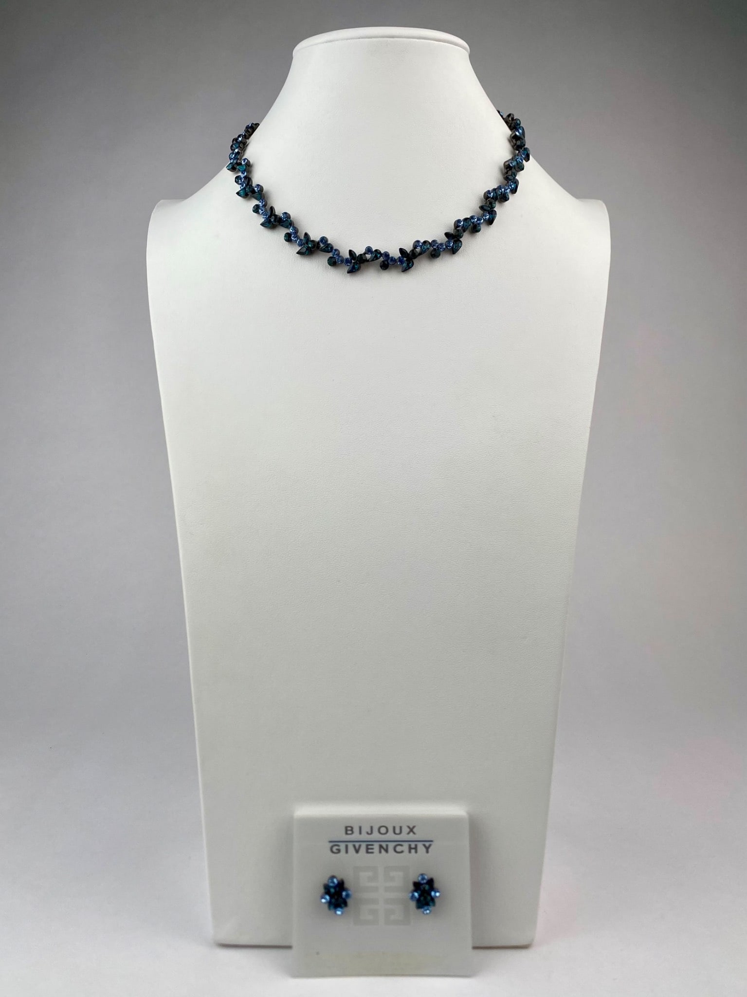 Givenchy Bijoux Blue Crystal Necklace and Earring Set: Givenchy Bijoux necklace and earring set featuring deep teal and light blue crystal rhinestones in a floral motif. The necklace is composed of alternating marquise and round-cut crystals in a gunmetal
