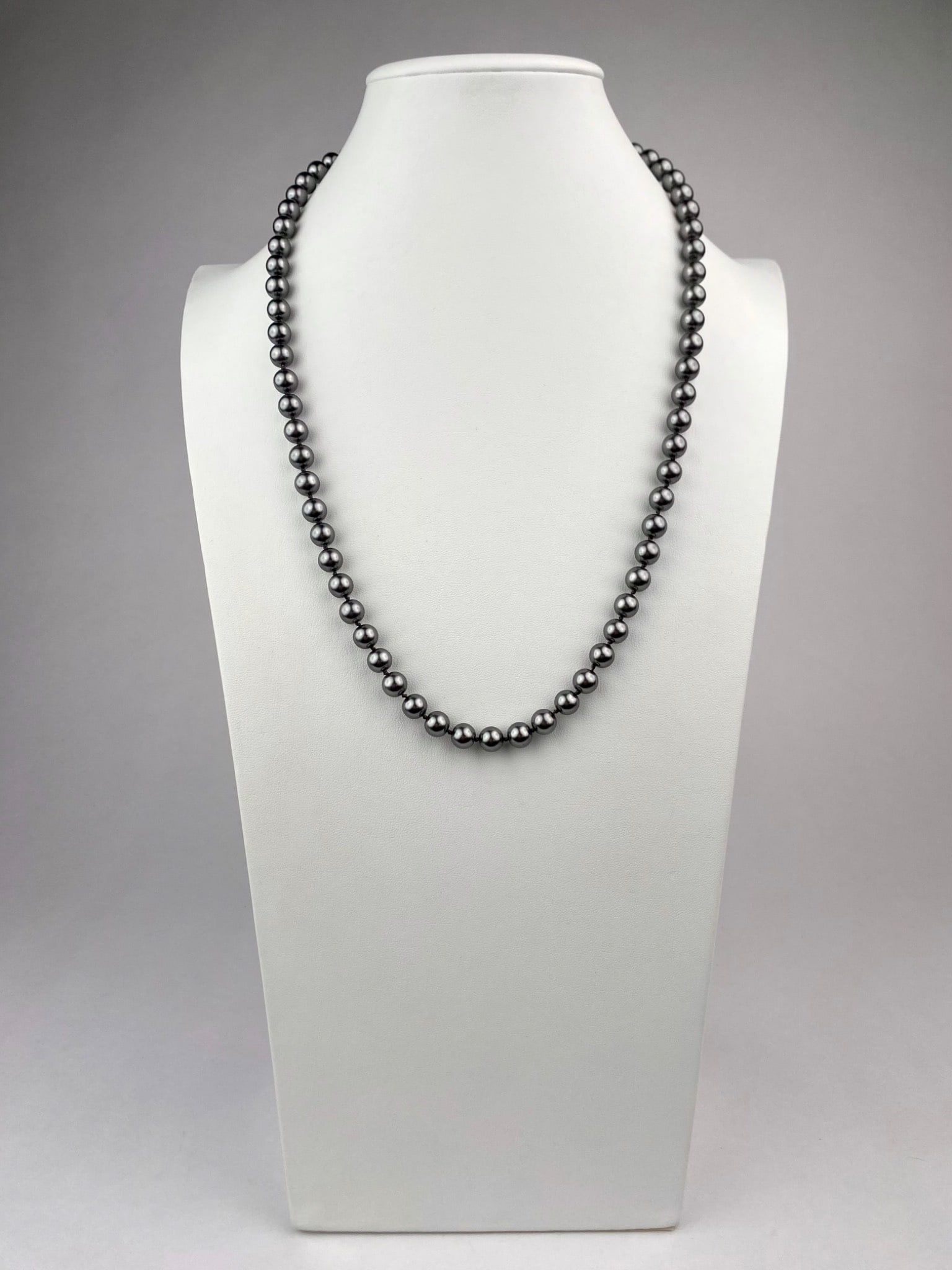 Strand of Graduated Black Pearls with Filigree Clasp: Single-strand necklace composed of graduated black pearls, each separated by hand knotted silk. The pearls display a silver gray-black hue. The necklace is finished with a filigree marquise-shaped cla
