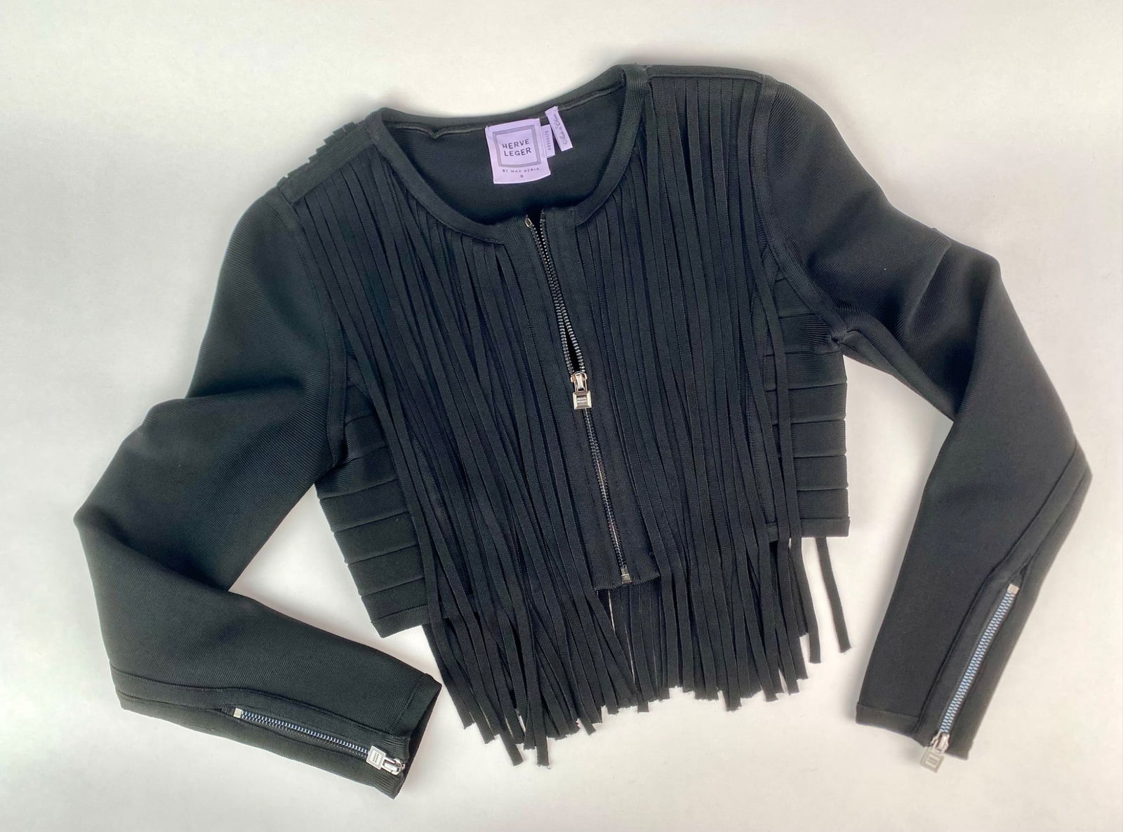 Herve Leger by Max Azria Black Bandage Fringe Cropped Jacket, Size S: Herve Leger by Max Azria black zip-front bandage jacket featuring dramatic vertical fringe detailing on both the front and back. The jacket is crafted in a body-con stretch knit with sculptural paneli