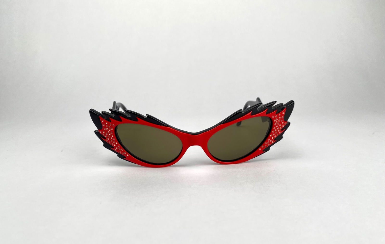 Harry Larrys Extasy Flame Style Sunglasses with Rhinestones: Harry Larry's Extasy flame-style sunglasses in a red and black design with rhinestone embellishments. The frames are crafted in France, featuring bold sculptural winged edges and tinted lenses. Th