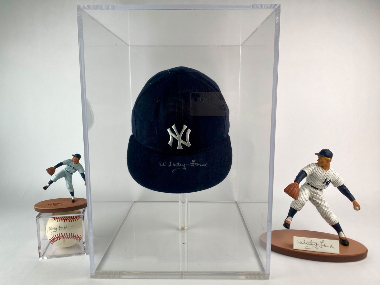 Whitey Ford Signed Memorabilia Four-Piece Set: Four-piece Whitey Ford memorabilia set including a New York Yankees cap hand-signed by Whitey Ford on the brim in silver ink, an official American League baseball with a clear signature by Whitey Ford