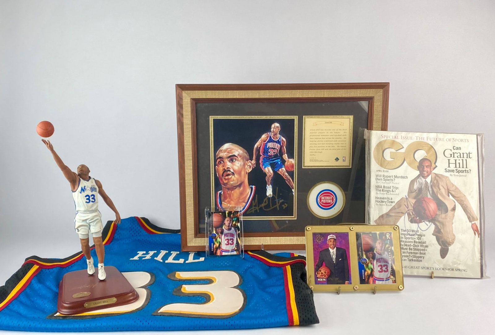 Grant Hill Autographed Memorabilia Collection: Collection featuring a variety of signed and collectible items celebrating NBA star Grant Hill. Included is a framed and matted lithograph of Hill in his Detroit Pistons uniform, signed in gold ink an