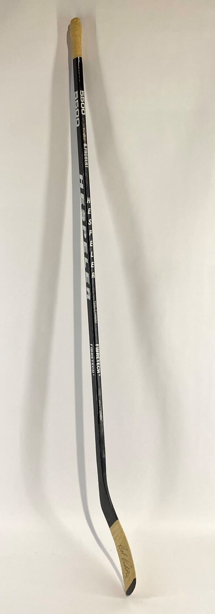 Bob Probert Signed Hespeler Kretech 5500 Hockey Stick: Hespeler Kretech 5500 hockey stick featuring taped handle and blade. Includes a signature on the blade in black marker from Bob Probert. The stick exhibits wear consistent with use, including scuffing