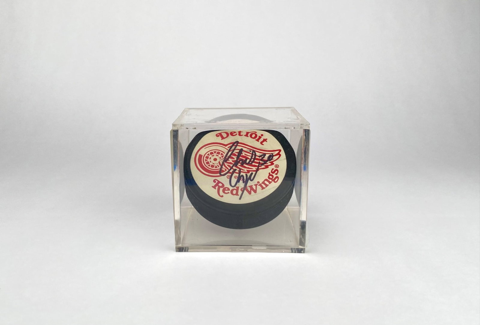 Detroit Red Wings Hockey Puck Signed by Chris Osgood in Case: Official NHL licensed Detroit Red Wings hockey puck autographed by Chris Osgood. The puck is housed in a clear acrylic display case that provides protection and visibility. The signature is prominentl