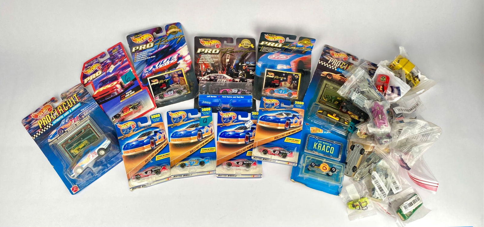 Hot Wheels Cars, Track Sets, and Assorted Miniature Vehicles: Hot Wheels cars in original packaging, including various models such as Pro Racing and other themed series. Includes additional assorted miniature vehicles in individual bags. Condition of items varie