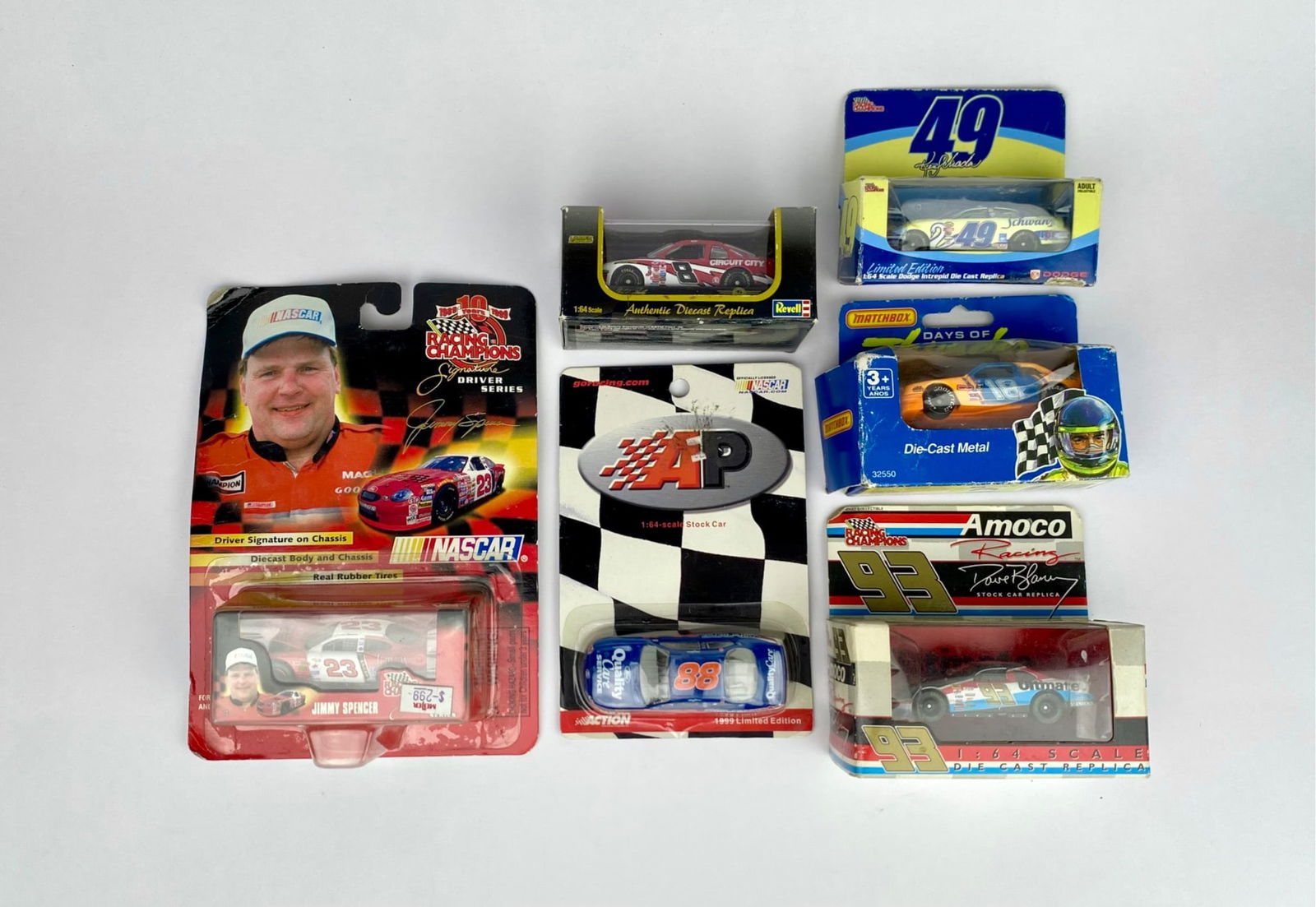 Six NASCAR Die-Cast Cars in Original Packaging: Six NASCAR die-cast cars in 1:64 scale, featuring various brands such as Revell, Matchbox, and Racing Champions. Includes multiple drivers, teams, and sponsors, with original packaging intact. Some pa