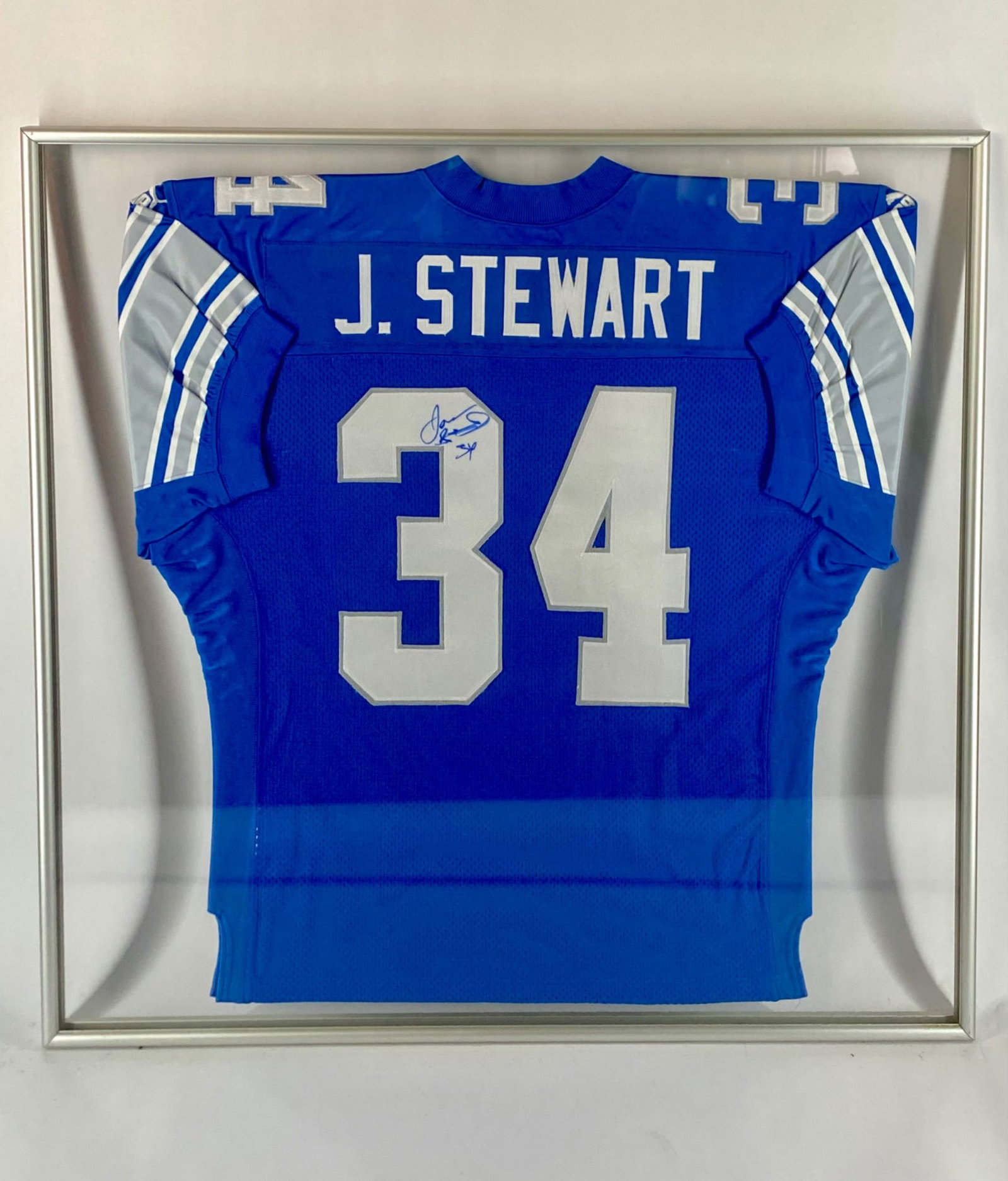 Jonathan Stewart Signed Detroit Lions Framed Jersey: Framed Detroit Lions home jersey, manufactured by Puma and tagged as an official licensed NFL product. The jersey features the classic Honolulu blue design with silver and white numbering, "J. Stewart