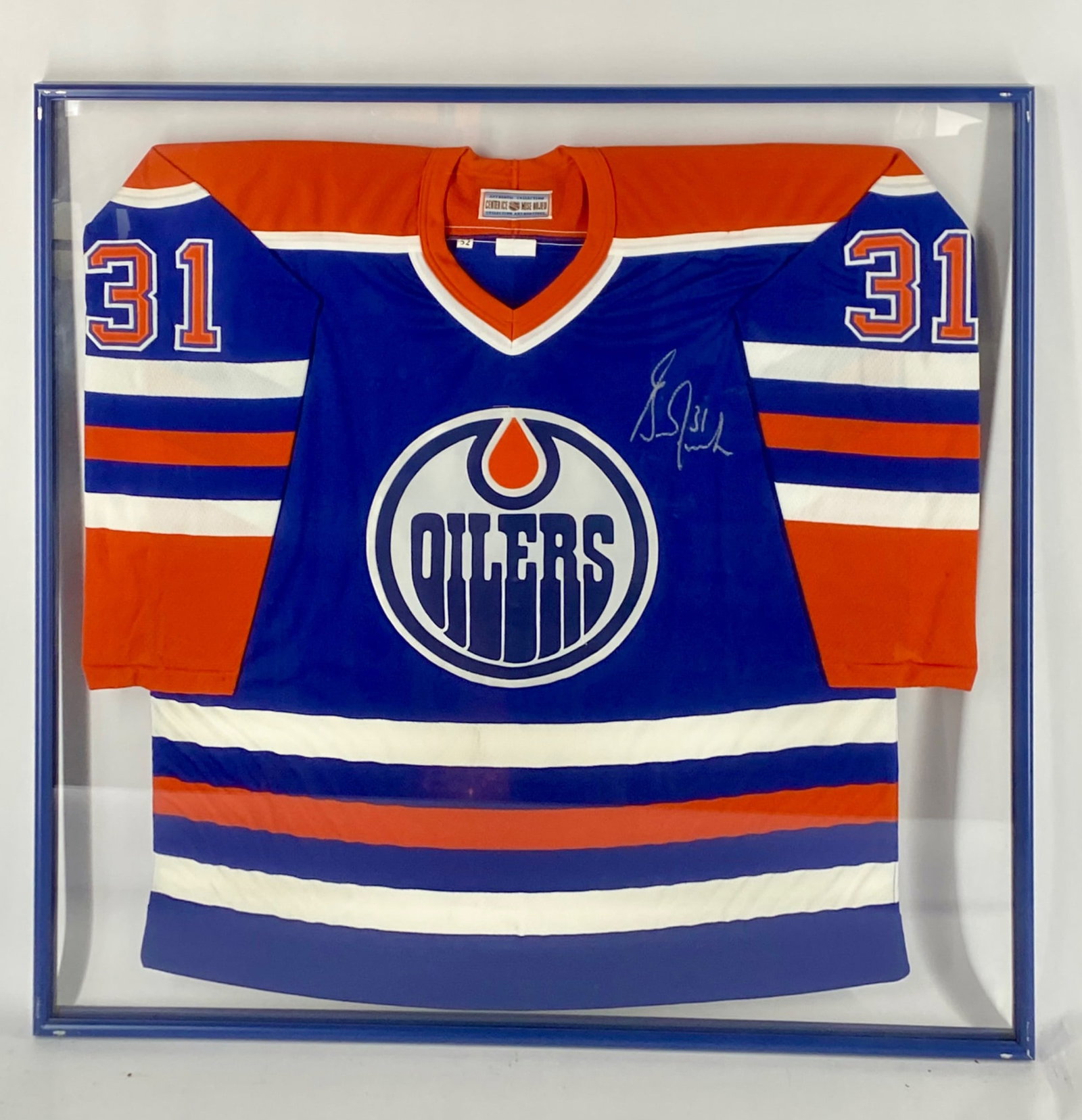 Grant Fuhr Signed Edmonton Oilers Authentic CCM Framed Jersey: Authentic Edmonton Oilers CCM "Center Ice Authentic" jersey featuring the classic blue, orange, and white team colors with the Oilers crest on the chest and FUHR 31 on the reverse. The jersey is signe